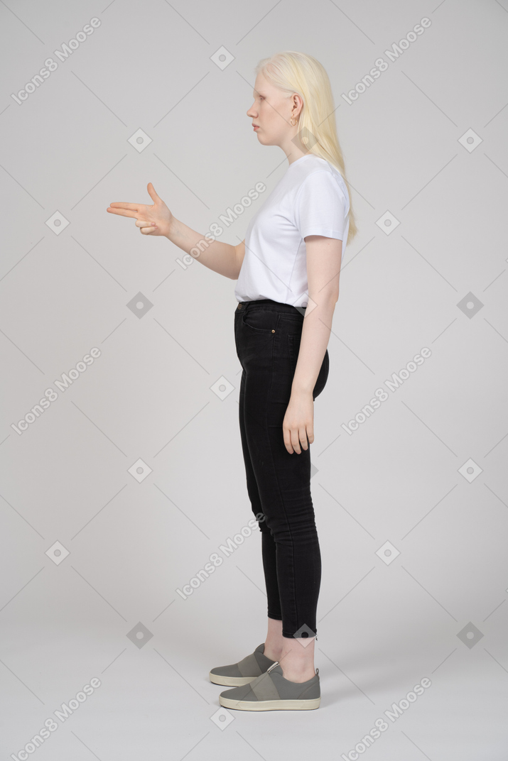 Vista lateral de uma mulher loira fazendo uma arma de dedo