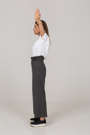 Side view of a young lady in office clothing holding hands together over her head