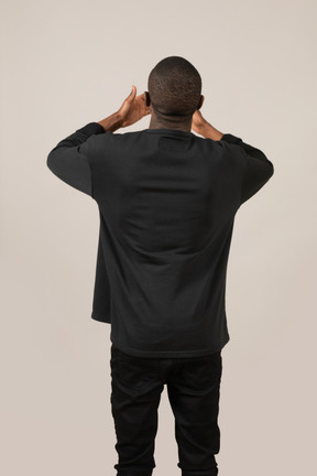 Back view of young man standing with hands on head