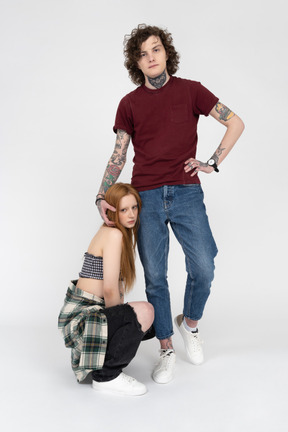 Teenage boy posing with his girlfriend squatting by his side