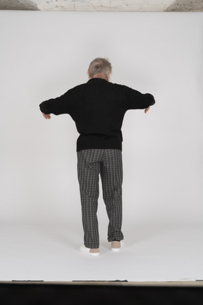 Rear view of old man standing with bent arms