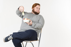 Bid bearded guy picked up salad leaf from the plate