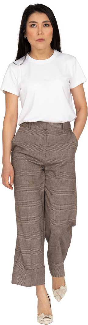 Vue de face d'une jeune femme marche sérieuse en culotte mettant la main dans la poche