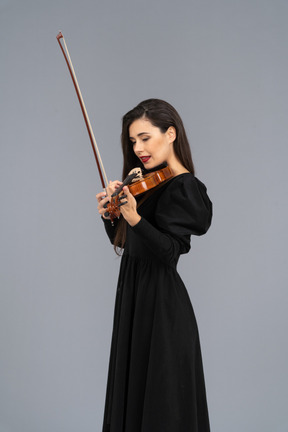 Close-up de uma jovem de vestido preto tocando violino