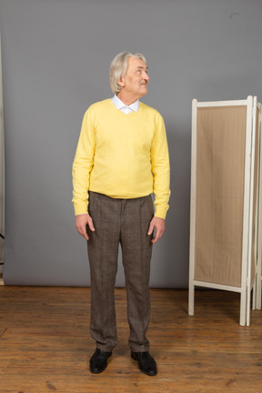 一个老人在黄色的套衫，抬头时转过头的前视图