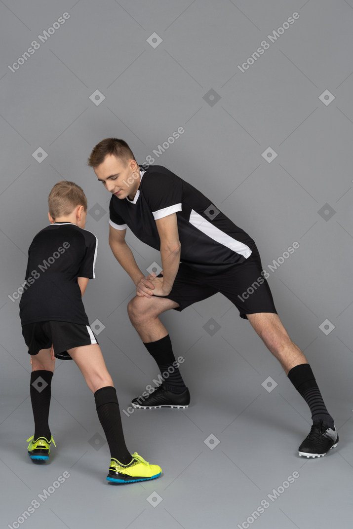 Full-length of a young man coaching little boy making a lunge