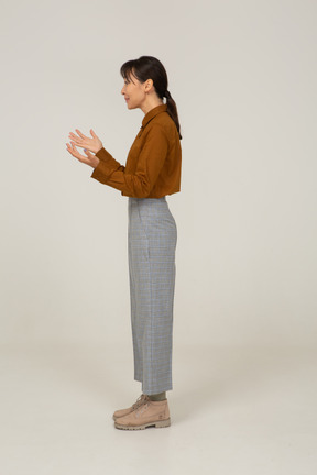 Side view of a young asian female in breeches and blouse raising hands