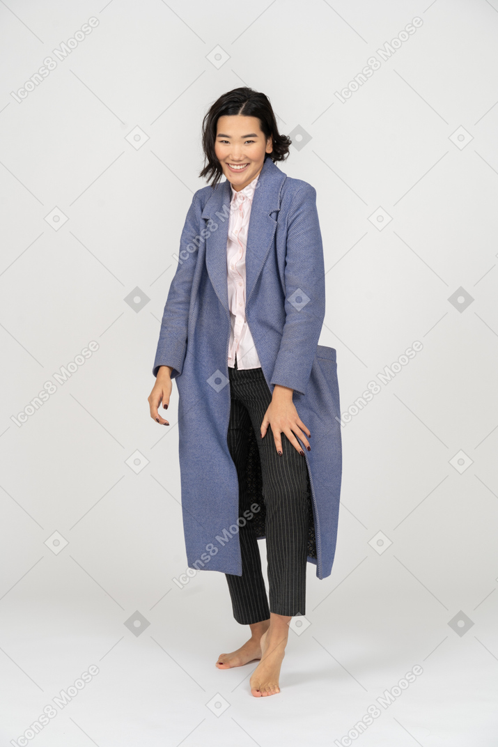 Молодая женщина в пальто улыбается и смотрит в камеру