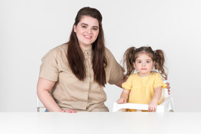 Madre e hijo niña hija en silla para niños sentados a la mesa