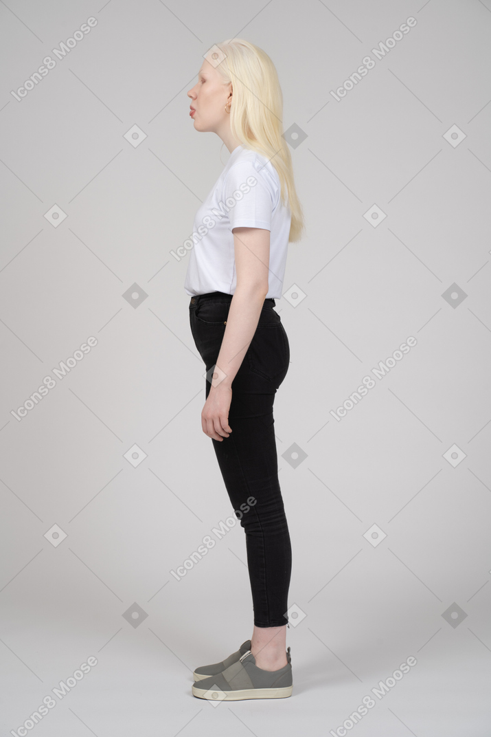 Vista de perfil de uma jovem em pé enfiando a língua para fora