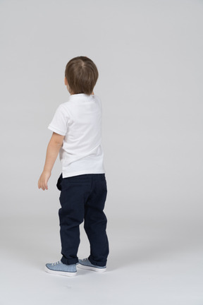 Back view of little boy standing and looking away