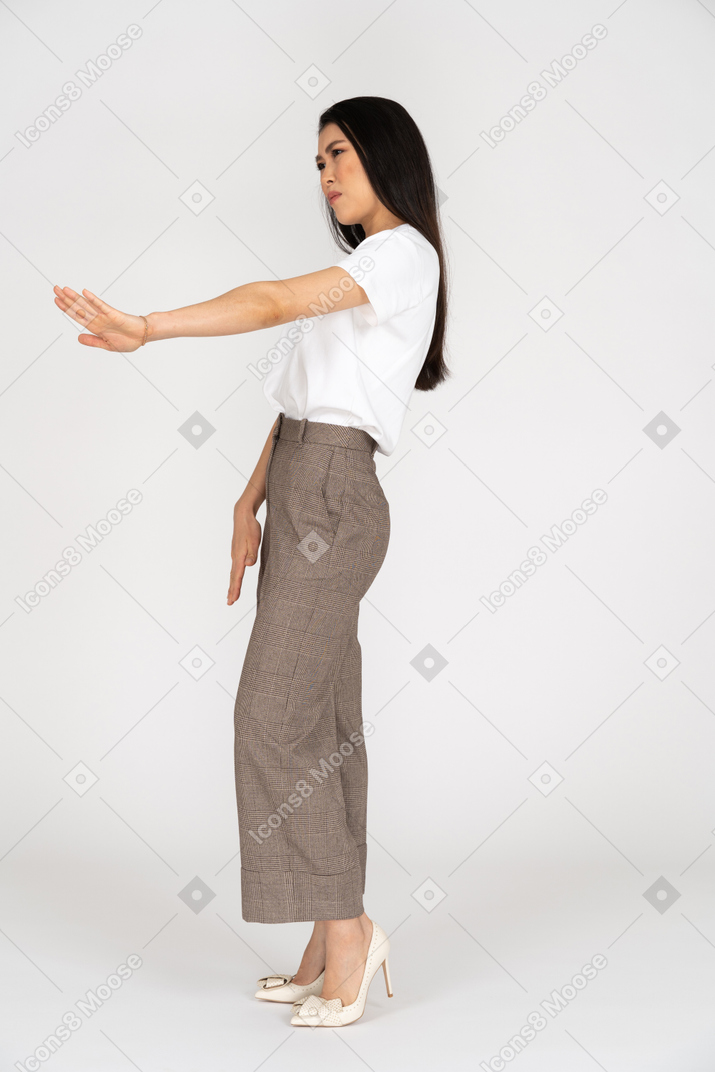 Side view of a young woman in breeches outstretching her hand