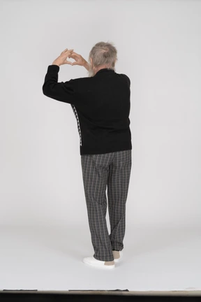 Rear view of old man showing heart gesture