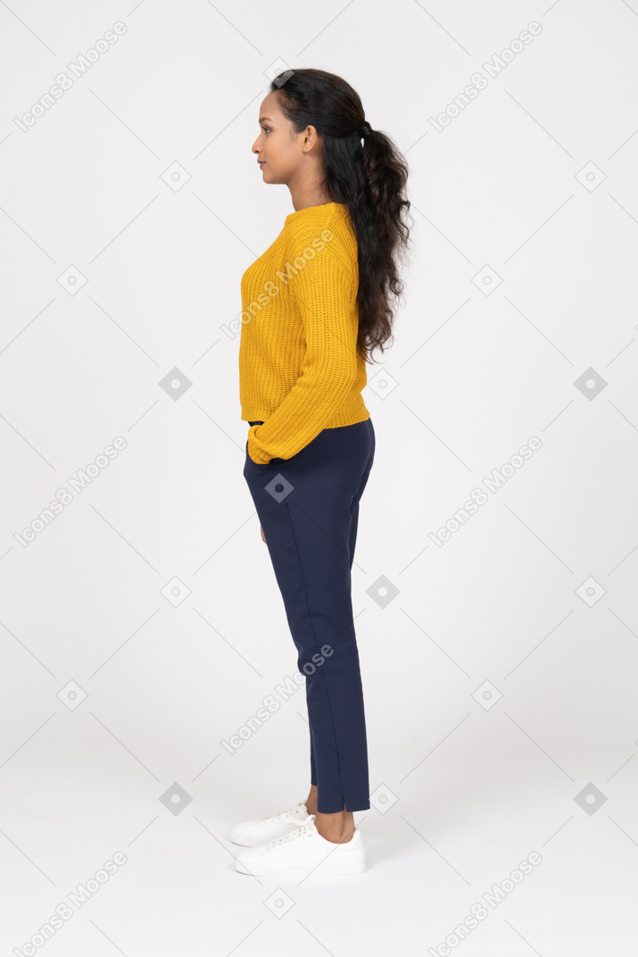 Vista laterale di una ragazza in abiti casual in piedi con la mano in tasca