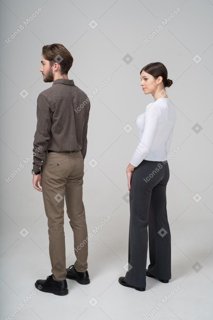 Vista posterior de tres cuartos de una pareja joven en ropa de oficina de pie todavía