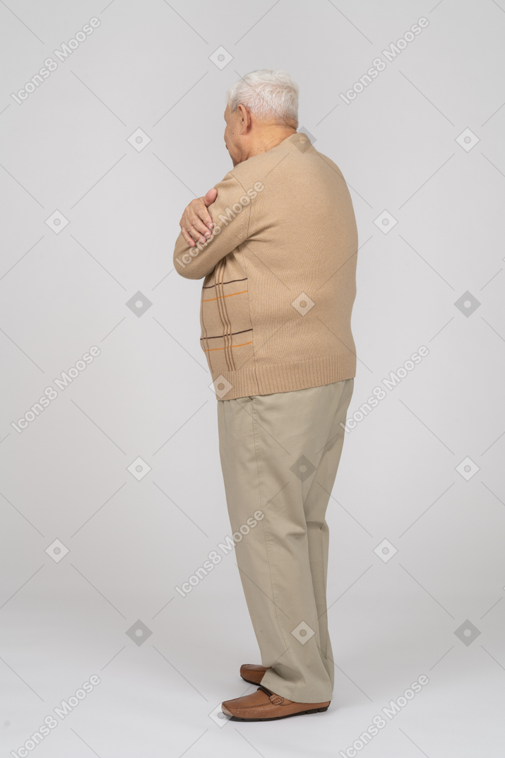 一位穿着休闲服的老人拥抱自己的侧视图