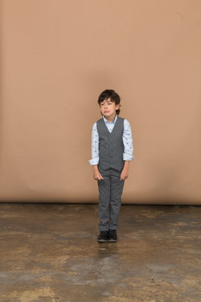 一个穿着灰色西装的男孩站着不动的前视图