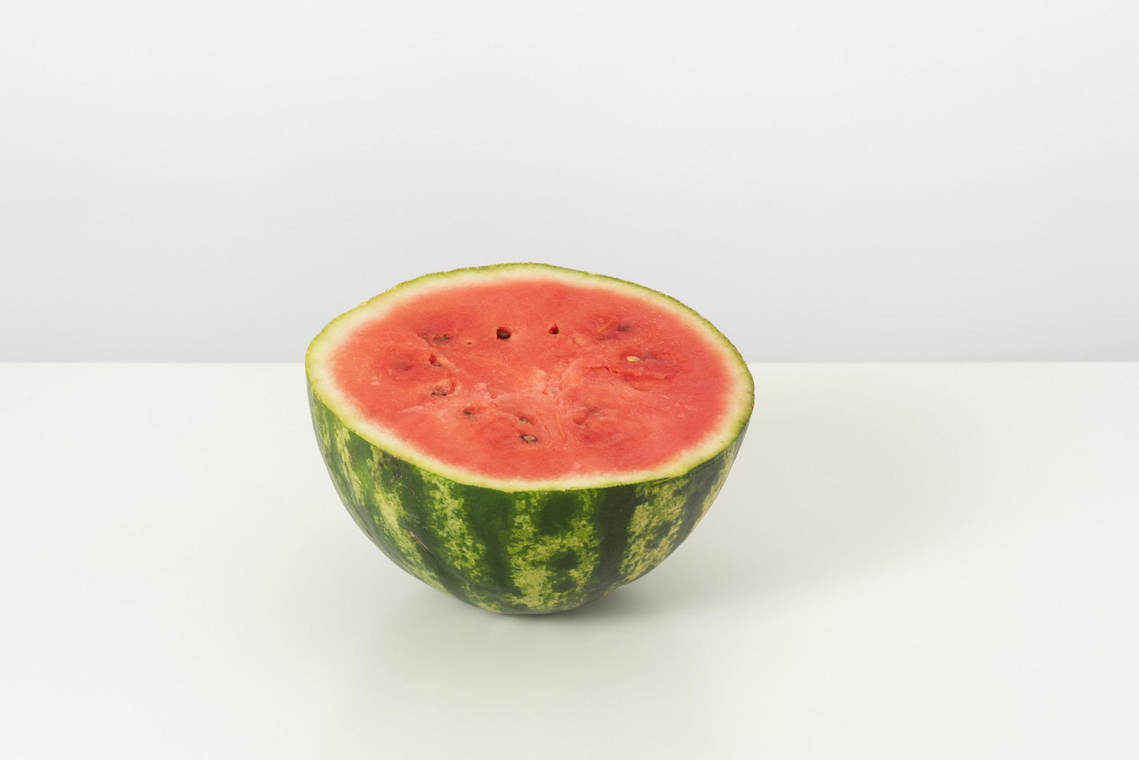 A half of a sweet ripe watermelon, lying isolated against a white background, looking nice and yummy