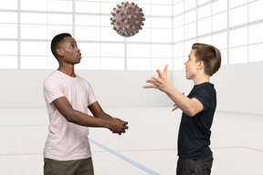 Two young men playing with a ball in a coronavirus shape