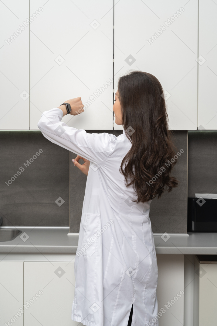 Back view of a woman in white coat checking the time
