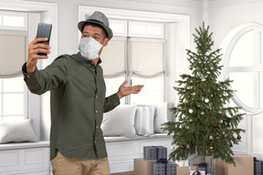 Man in a mask shows a christmas tree during a video call