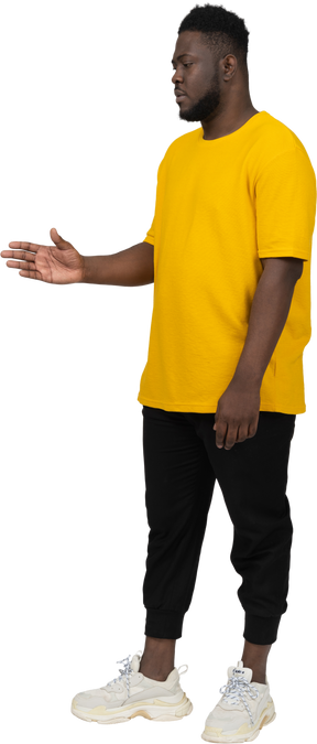 Three-quarter view of a young dark-skinned man in yellow t-shirt outstretching his arm
