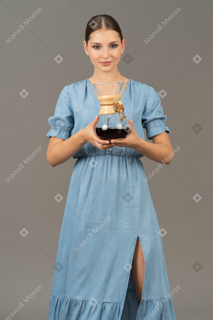 Front view of a young woman in blue dress holding a pitcher of wine