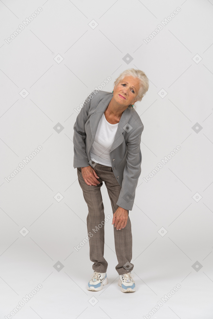Vista frontal de una anciana en traje tocando su rodilla lastimada