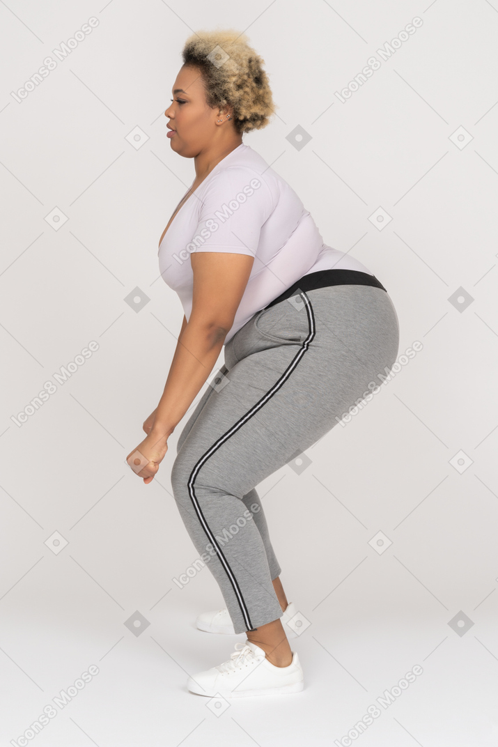 Женщина больших размеров сгибает колени в профиль