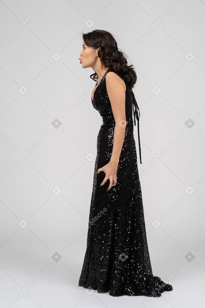 Bella donna in abito da sera nero in piedi di profilo e piangendo a qualcuno