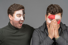 Front view of two male football fans sharing their emotions