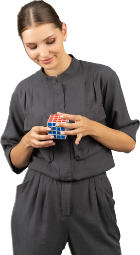 Front view of a smiling young woman in a jumpsuit holding the rubik's cube