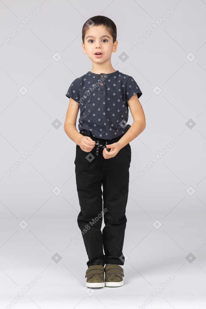 Vista frontal de um lindo menino em roupas casuais, olhando para a câmera