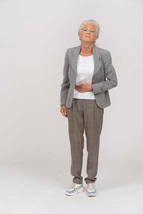 Vorderansicht einer alten dame im anzug mit bauchschmerzen
