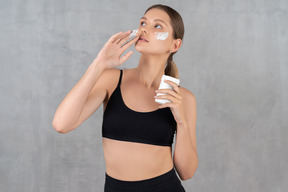 Mulher aplicando creme hidratante no rosto