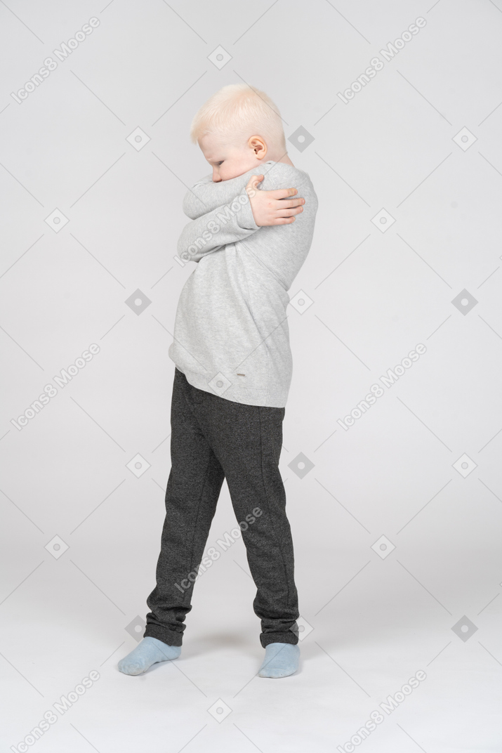 Little boy hugging himself and turning away