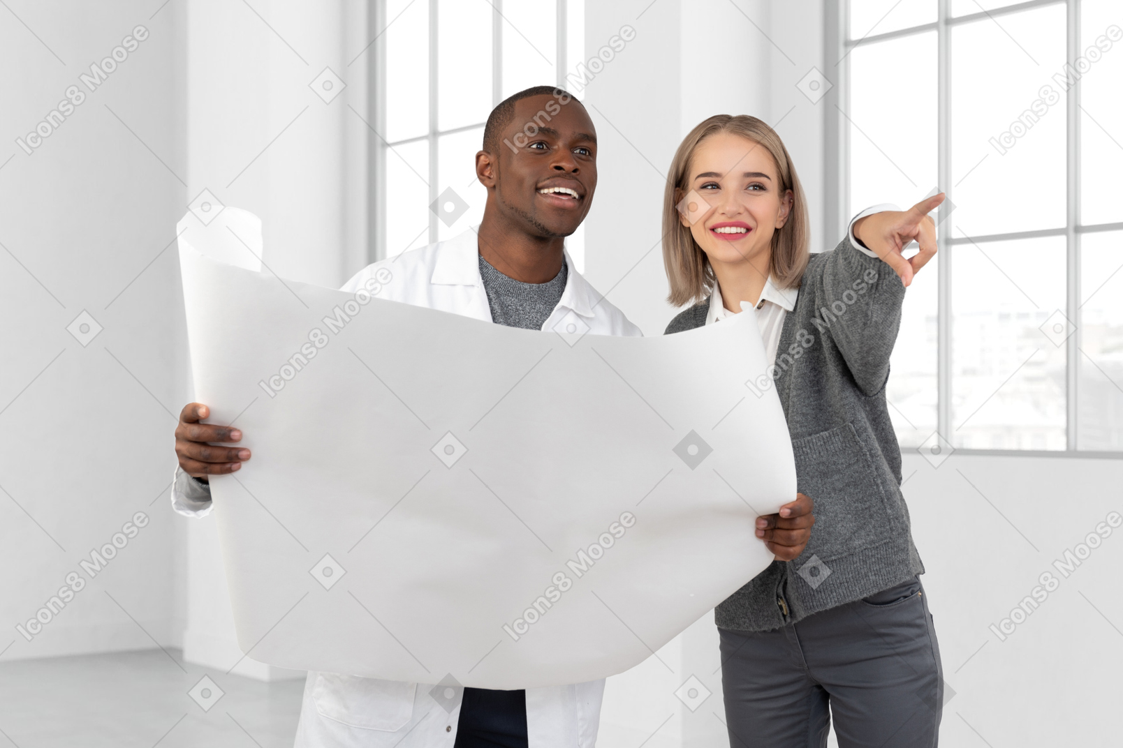 Man and woman holding a large sheet of paper and pointing at something