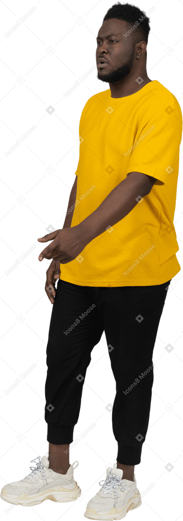 Vista di tre quarti di un giovane uomo dalla pelle scura gesticolante in maglietta gialla che spiega qualcosa