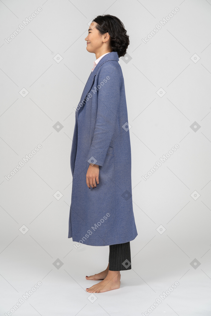 Vista laterale di una donna sorridente in cappotto blu