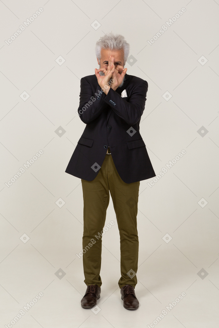 Homem de casaco fazendo um gesto com a mão sobre o rosto