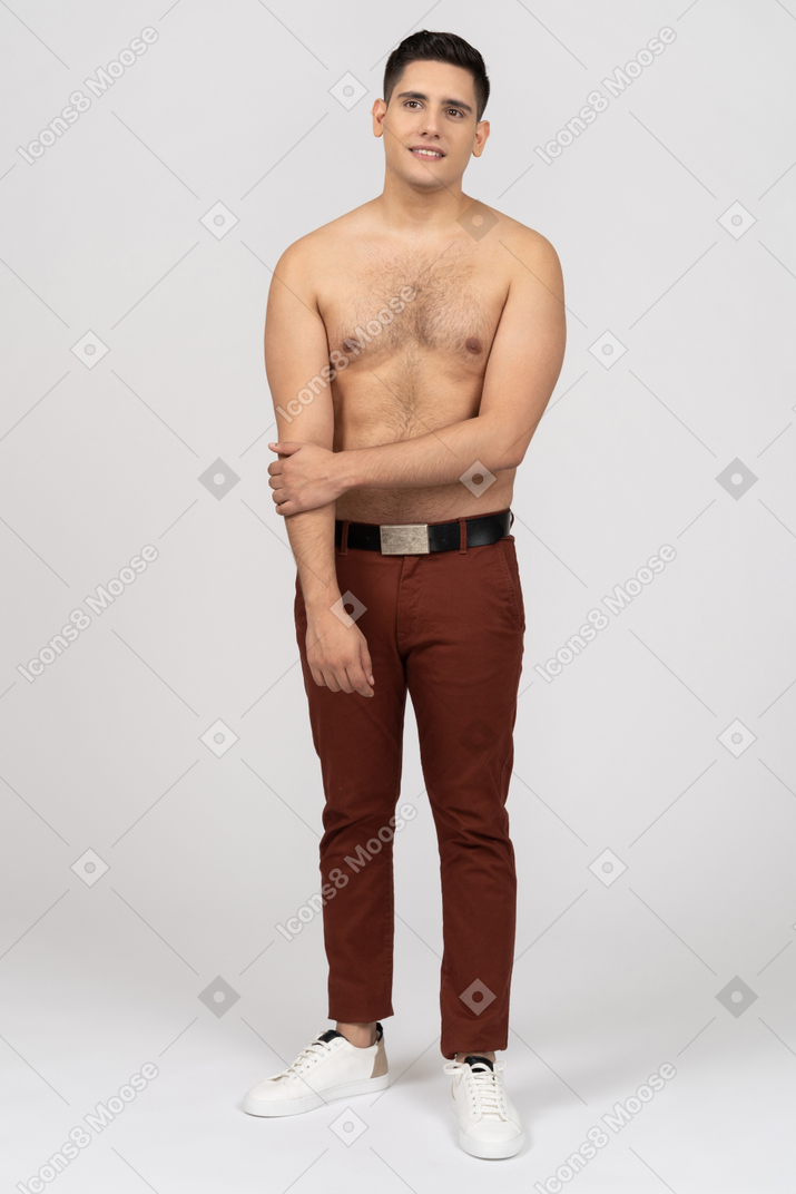 Front view of a shirtless latino man smiling uncertainly