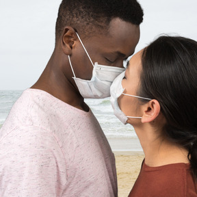 A man and a woman kissing each other with face masks on