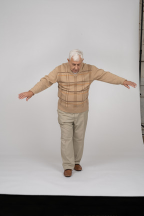 Vista frontal de um velho em roupas casuais, caminhando para a frente com os braços estendidos