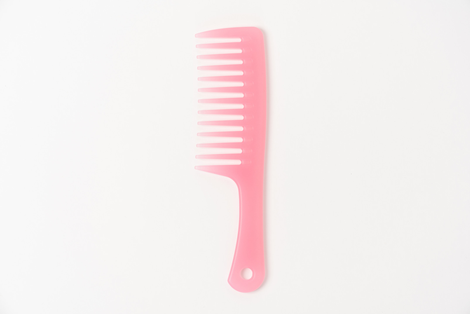 Pink plastic comb on white background