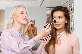 A woman doing another woman's makeup