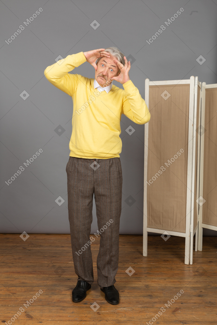 Front view of a funny grimacing old man touching his head