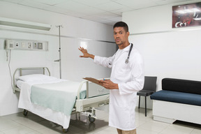 A male doctor standing next to a bed in a hospital room