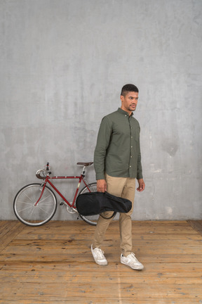 Front view of a man carrying a ukulele case