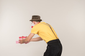 Male clown holding gift box and standing back to camera