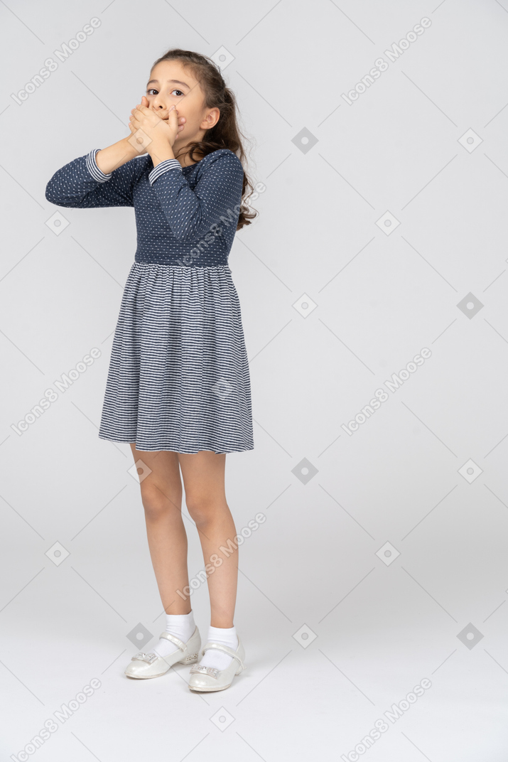Three-quarter view of a girl covering her mouth with both hands